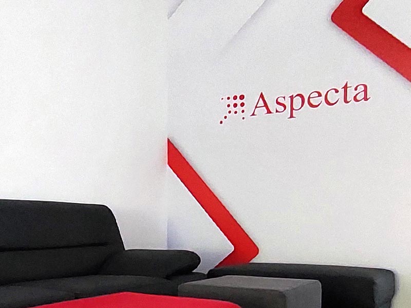 Logo Aspecty na stene kancelárie nad sedačkou